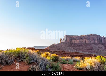 View of mesa butte formations with red orange rock color in Monument Valley canyons during sunset in Arizona with sunlight over cabin houses in campgr Stock Photo