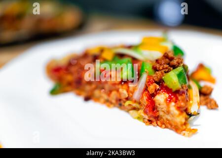 Homemade baked pizza slice on one white plate serving with tomato sauce and toppings such as green bell peppers with macro shot and bokeh background Stock Photo