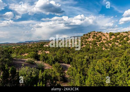 Sunset evening in Santa Fe, New Mexico Tesuque community neighborhood in Rocky Mountain foothills with houses and green plants pinyon trees shrubs and Stock Photo