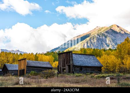 Aspen, Colorado Ashcroft Ghost Town in Castle Creek abandoned wooden house cabins with yellow foliage aspen trees and rocky mountain peak with blue sk Stock Photo