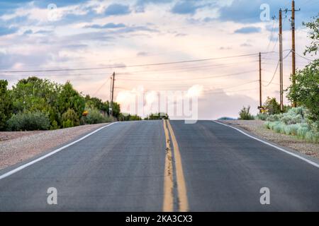 Colorful sunset on Bishops Lodge Road in Santa Fe, New Mexico with golden light, green plants and road to residential community Stock Photo