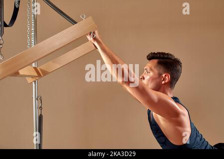 Handsome pilates male instructor performing stretching balance fitness  exercise on small barrel equipment, at the pilates studio modern onterior  indoo Stock Photo - Alamy