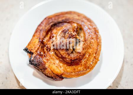 Macro closeup flat top lay of fresh barbecue cooked baked pork belly fat spiral meat, nutritious food on white plate at kitchen table Stock Photo