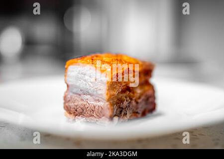 Macro closeup side view of cut fresh barbecue cooked baked fried pork belly fat bacon meat with crispy crunchy skin, nutritious food isolated against Stock Photo