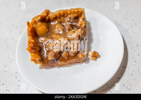 Macro closeup of one cooked piece of pecan pie with dough crust on plate isolated on white background Stock Photo