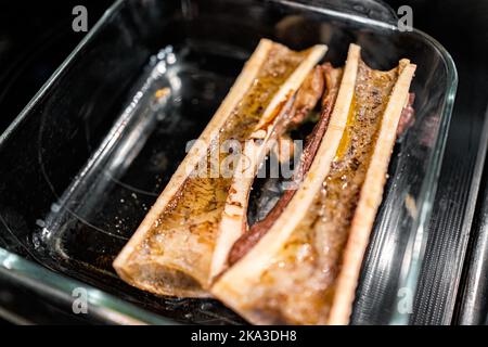 Macro closeup of marrow beef bones split in half baked on cooking tray in oven with liquid fat collagen Stock Photo