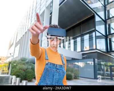 Cheerful woman in VR goggles interacting with virtual reality while playing video game on sunny day Stock Photo