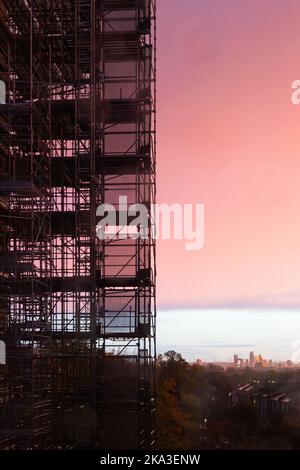 Scaffolding around modern building during renovations with sunset sky Stock Photo