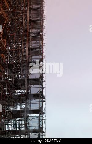 Scaffolding around modern building during renovations with sunset sky Stock Photo