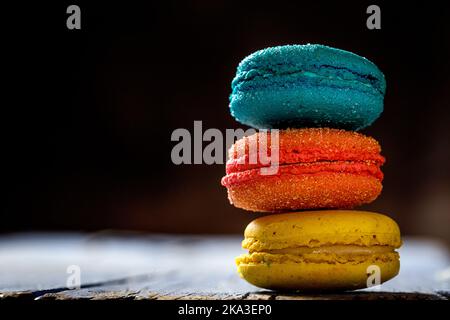 Colorful French macaroons with various fillings placed on wooden table in dark background Stock Photo