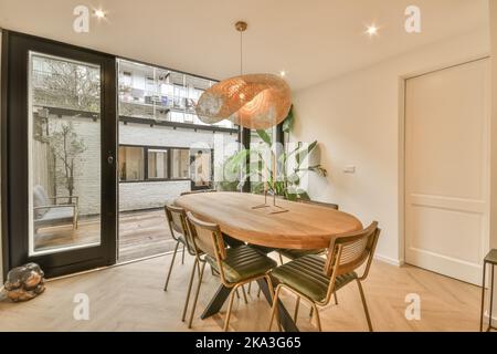 Chairs at wooden table placed in light spacious dining room in modern apartment with opened doors leading to balcony Stock Photo