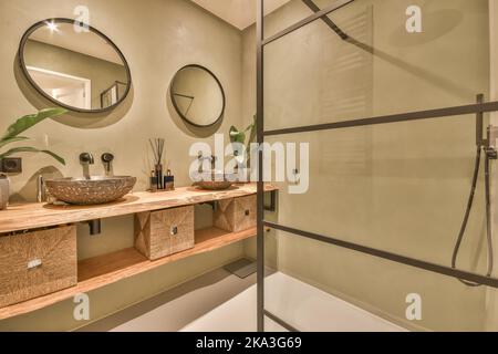 Sinks with taps installed on wooden shelf under mirror in light bathroom of modern apartment near shower Stock Photo