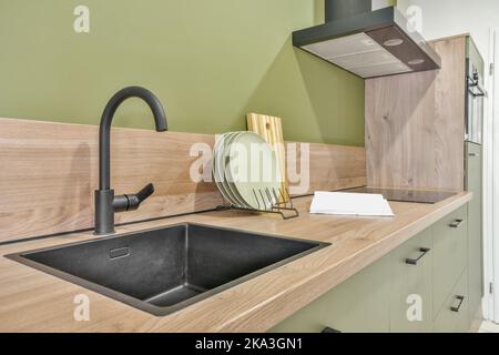 Contemporary metal faucet over sink on counter in contemporary kitchen in new apartment Stock Photo