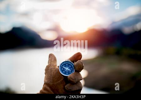 Soft focus of crop anonymous person holding small round compass in hand in suede glove near picturesque mountainous valley Stock Photo