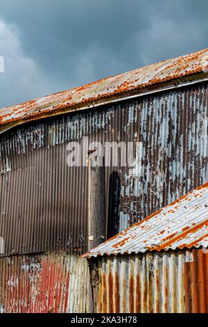 Detail of a corrugated iron wall on a metal building with signs of rust and decay. Stock Photo