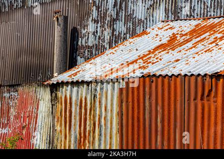 Detail of a corrugated iron wall on a metal building with signs of rust and decay. Stock Photo