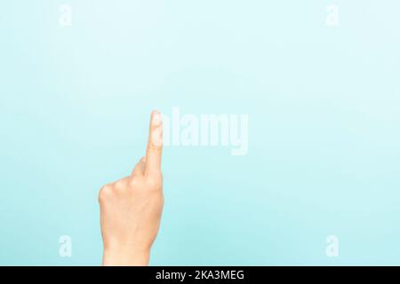 Hand gesture show, touch, index, press, select something. Woman pointing up with index finger on light blue background. Female hand shows number one Stock Photo
