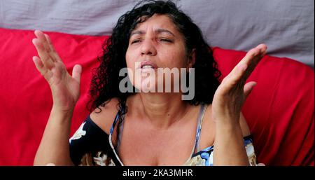 Evangelical Brazilian woman praying to God. Spiritual mature person praising God Stock Photo