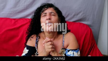 Evangelical Brazilian woman praying to God. Spiritual mature person praising God Stock Photo