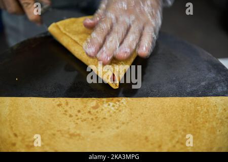 Making delicious crepes on a grill with fruit and chocolate Stock Photo