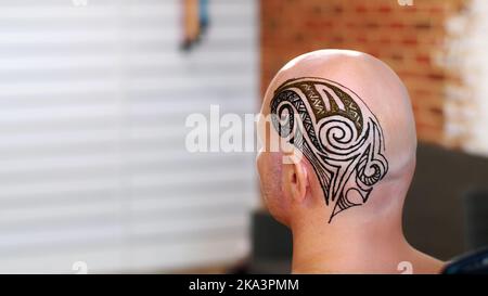 A close-up of the drawing, ornament, henna tattoo, on the scalp, shoulder, neck. The solution of henna dries on the skin. The process of applying henna from a tube to the skin. High quality photo Stock Photo
