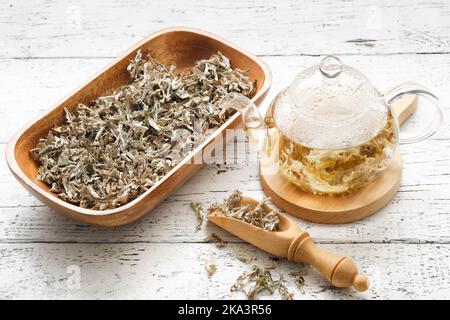 Glass teapot of herbal Icelandic moss tea. Wooden scoop and bowl of dried Iceland moss. Cetraria islandica - latin name of plant. Alternative herbal m Stock Photo