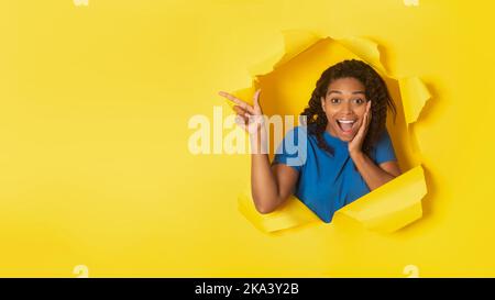 Black Lady Pointing Finger Aside At Torn Yellow Paper Background Stock Photo