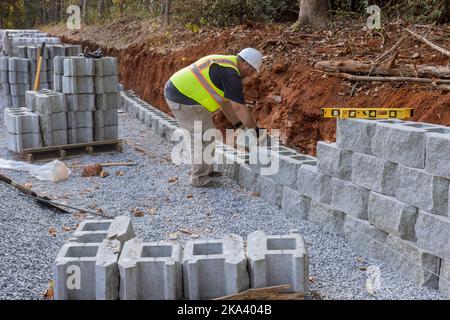 Construction worker is constructing retaining block wall on new property that is being built Stock Photo