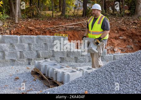 Building retaining wall with retaining blocks on new property is being done by construction worker Stock Photo