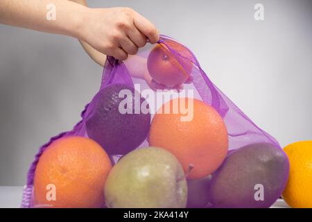 A woman puts fruit in a net. The concept of abandoning plastic shopping bags Stock Photo