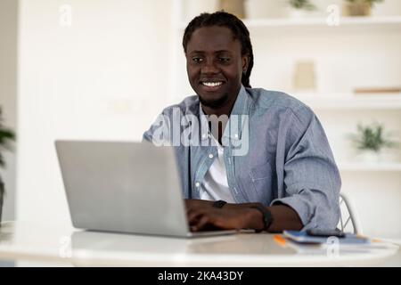 Freelance Career. Portrait Of Young Smiling Black Man Working With Laptop Stock Photo