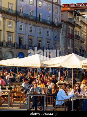 PORTO, PORTUGAL - NOVEMBER 7, 2021: People sitting in cafe and street restaurants at central embankment, crowded touristic area, traditional architect Stock Photo