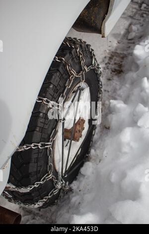 Closeup of a tire with chains in the winter snow. Stock Photo