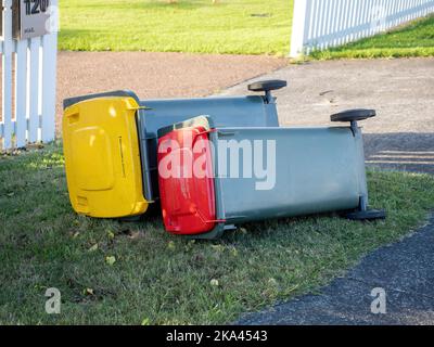 View of rubbish wheelie bins toppled by strong wind laying on ground Stock Photo