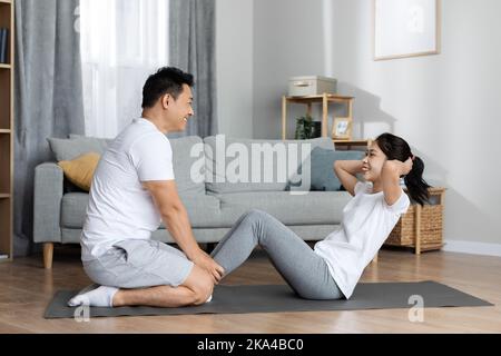 Side view of athletic korean man and woman exercising together Stock Photo