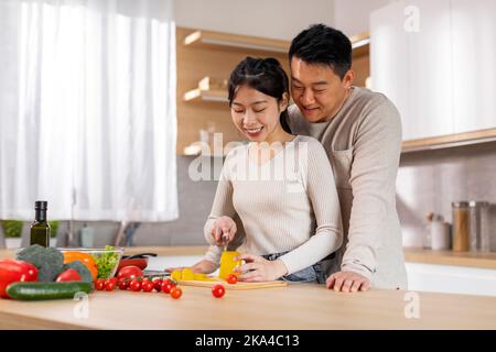 Positive korean spouses spending time together at home, cooking Stock Photo