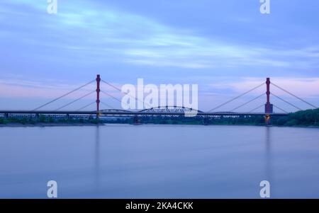 Long exposure at blue hour on the Rhine in front of an illuminated highway bridge. the bridge connects the Ruhr area with the Lower Rhine. Stock Photo