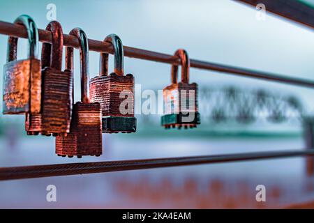 A closeup shot of hanging rusty padlocks on a steel wire Stock Photo