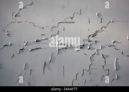 Rain water leaks on white painted wall causing damage and peeling paint. Grunge building wall with cracks in stucco and paint. Closeup Stock Photo