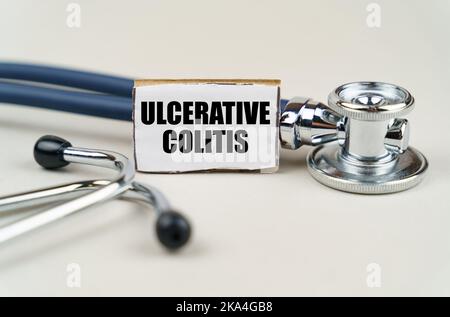 Medical concept. On a gray background, a stethoscope and a cardboard sign with the inscription - Ulcerative colitis Stock Photo