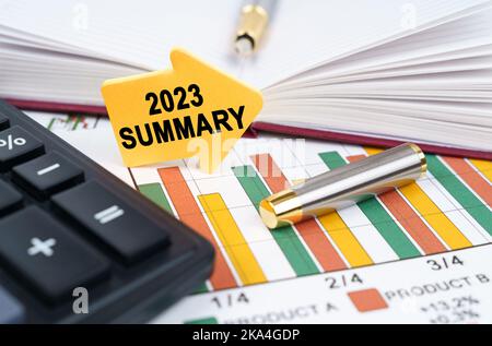 Business concept. On the business charts there is a notepad, a pen and an arrow sticker with the inscription - 2023 Summary Stock Photo