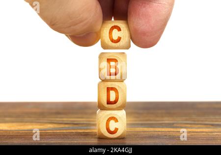 Business concept. A man puts wooden cubes on the table with the inscription - CBDC Stock Photo