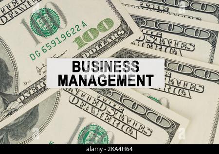 Business concept. On the dollars lies a paper plate with the inscription - BUSINESS MANAGEMENT Stock Photo