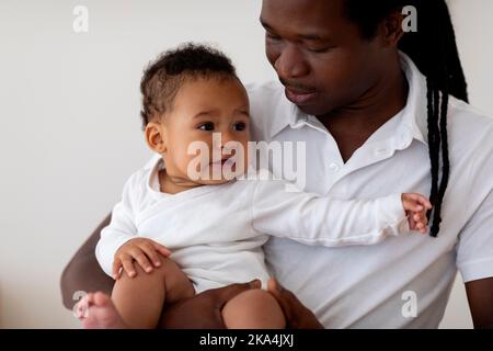 Baby Mood Swings. Black Father Holding Cute Crying Infant Child In Arms Stock Photo