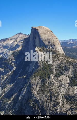 Towering over Yosemite valley stands the wondrous rock formation of Half Dome.  It stands against the background of an endless sky. Stock Photo