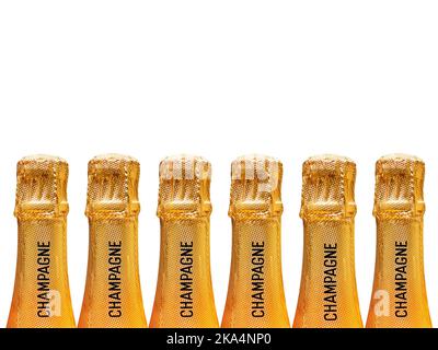 Row of champagne bottles covered in gold foil stamped with the word champagne on the neck against a plain pink background. No people. Copy space. Stock Photo