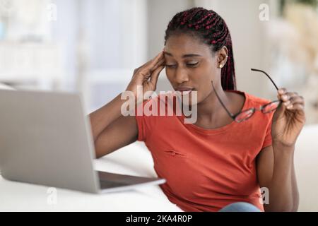 Stressed Black Freelancer Lady Having Headache While Working With Laptop At Home Stock Photo