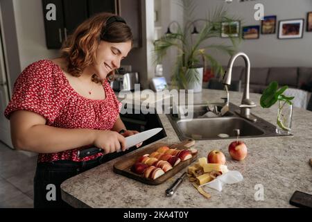 Young adult women making pastry with apples cutting apples and smiling Stock Photo