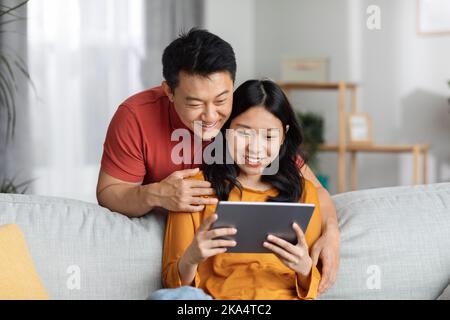 Positive chinese spouses using digital tablet, having video call Stock Photo