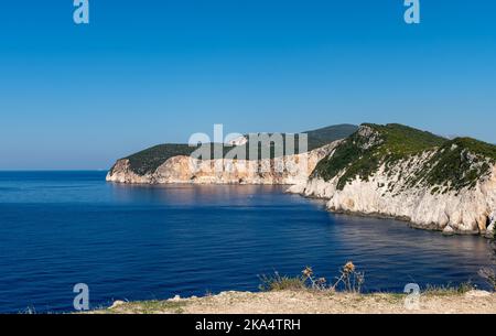 Headland cliffs sliding into deep blue sea on a beautiful cloudless day with blue sky. Stock Photo